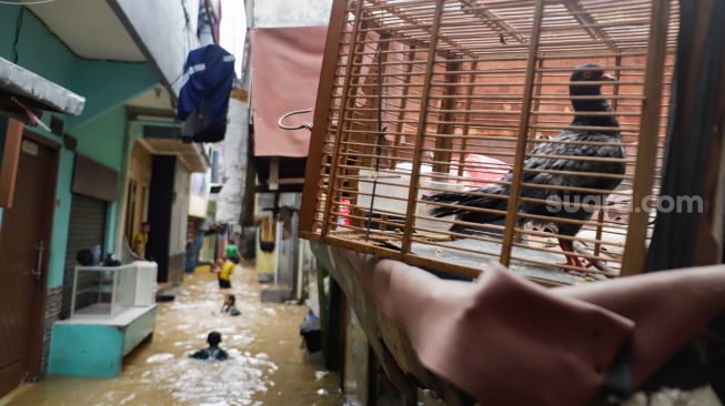 Warga beraktivitas saat banjir yang melanda kawasan Kebon Pala, Jakarta Timur, Senin (10/10/2022). [Suara.com/Alfian Winanto]