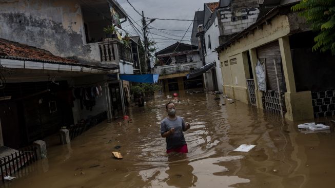 Warga berjalan melintasi banjir di permukiman penduduk kawasan Rawajati, Jakarta, Senin (10/10/2022). [ANTARA FOTO/Aprillio Akbar/aww].