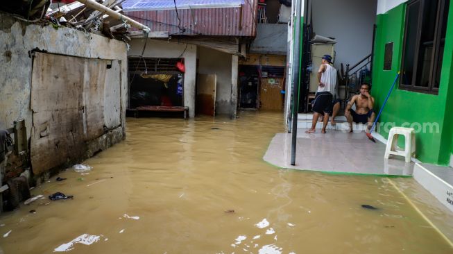 Warga beraktivitas saat banjir yang melanda kawasan Kebon Pala, Jakarta Timur, Senin (10/10/2022). [Suara.com/Alfian Winanto]