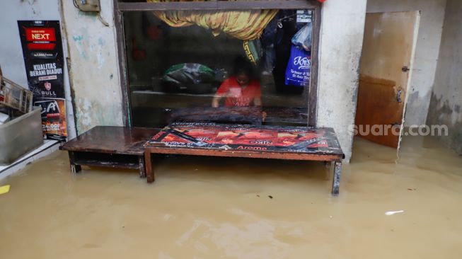 Warga beraktivitas saat banjir yang melanda kawasan Kebon Pala, Jakarta Timur, Senin (10/10/2022). [Suara.com/Alfian Winanto]