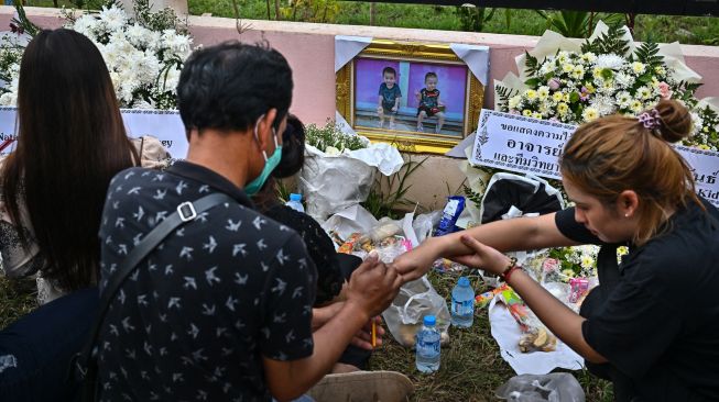 Keluarga korban berkumpul untuk doa bersama dan upacara keagamaan di luar tempat penitipan anak, yang menjadi lokasi penembakan massal di kota Uthai Sawan, Nong Bua Lam Phu, Thailand, Minggu (9/10/2022). [Lillian SUWANRUMPHA / AFP]
