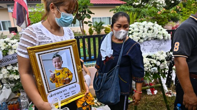 Keluarga korban berkumpul untuk doa bersama dan upacara keagamaan di luar tempat penitipan anak, yang menjadi lokasi penembakan massal di kota Uthai Sawan, Nong Bua Lam Phu, Thailand, Minggu (9/10/2022). [Lillian SUWANRUMPHA / AFP]