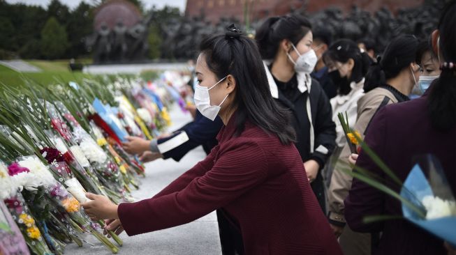 Orang-orang meletakkan bunga untuk memberi penghormatan di depan patung pemimpin Korea Utara Kim Il Sung dan Kim Jong Il di Bukit Mansu, Pyongyang, Korea Utara, Senin (10/10/2022). [KIM Won Jin / AFP]
