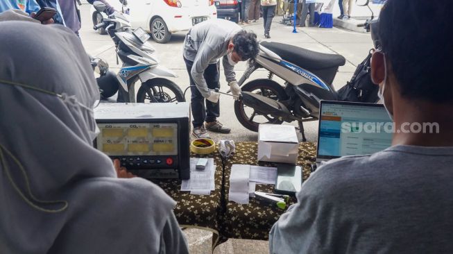 Petugas melakukan uji emisi kendaraan bermotor di  Terminal Blok M, Jakarta Selatan, Selasa (11/10/2022). [Suara.com/Alfian Winanto]