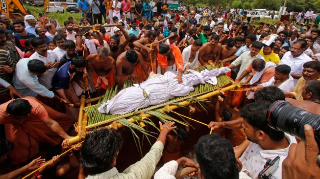 Orang-orang membawa mayat buaya bernama Babiya dari kuil danau Ananthapura untuk dimakamkan di kuil Swamy Ananthapadmanabha di Kasaragod, Kerala, India, Senin (10/10/2022). [AFP]