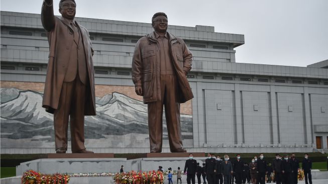 Orang-orang memberi penghormatan di depan patung pemimpin Korea Utara Kim Il Sung dan Kim Jong Il di Bukit Mansu, Pyongyang, Korea Utara, Senin (10/10/2022). [KIM Won Jin / AFP]