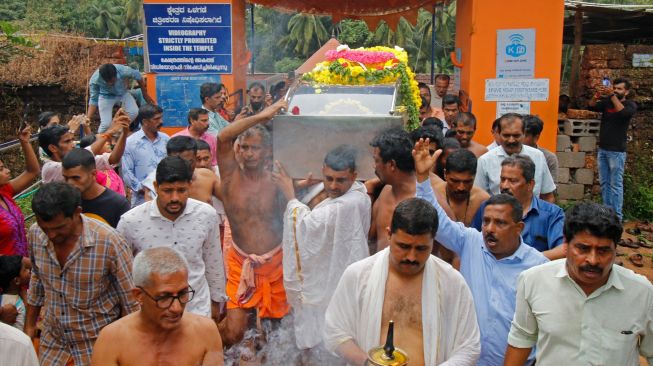 Orang-orang membawa mayat buaya bernama Babiya dari kuil danau Ananthapura untuk dimakamkan di kuil Swamy Ananthapadmanabha di Kasaragod, Kerala, India, Senin (10/10/2022). [AFP]