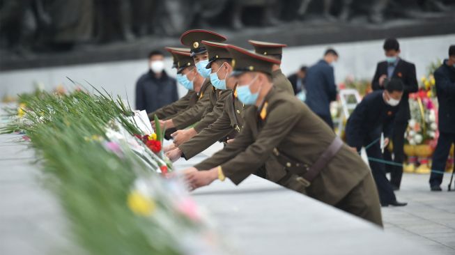 Para tentara meletakkan bunga untuk memberi penghormatan di depan patung pemimpin Korea Utara Kim Il Sung dan Kim Jong Il di Bukit Mansu, Pyongyang, Korea Utara, Senin (10/10/2022). [KIM Won Jin / AFP]