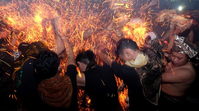 Sejumlah pemuda saling memukulkan api dari sabut kelapa saat tradisi "Mesiat Geni" atau perang api di Desa Tuban, Badung, Bali, Senin (10/10/2022).  ANTARA FOTO/Nyoman Hendra Wibowo