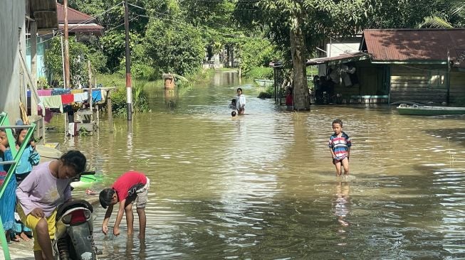 Sejumlah anak berjalan melintasi banjir yang merendam permukiman di Sungai Ana Baning, Kecamatan Sintang, Kabupaten Sintang, Kalimantan Barat, Senin (10/10/2022). [Antara Foto]
