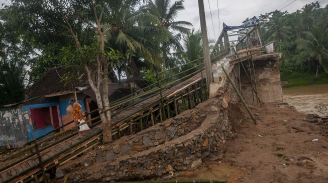 Warga berjalan di jembatan sementara di Sukajaya, Lebak, Banten, Selasa (11/10/2022). ANTARA FOTO/Muhammad Bagus Khoirunas