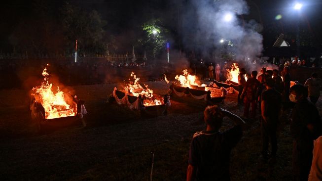 Orang-orang menyaksikan peti mati korban penembakan massal dibakar selama upacara kremasi di Na Klang, Provinsi Nong Bua Lam Phu, Thailand, Selasa (11/10/2022). [Lillian SUWANRUMPHA / AFP]