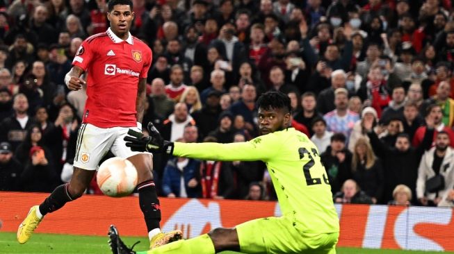 Aksi kiper Omonia Nicosia, Francis Uzoho (kanan) menahan tendangan penyerang Manchester United Marcus Rashford dalam laga Liga Europa di Old Trafford, Manchester, Jumat (14/10/2022) dini hari WIB. [Oli SCARFF / AFP]