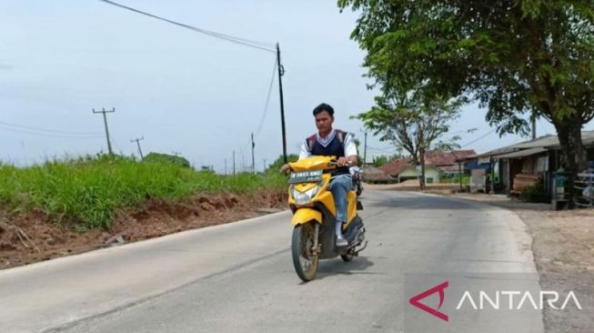 Seorang pengendara sepeda motor melintasi Ruas Jalan Cigutul-Cibenda yang sedang diperbaiki dengan progres pekerjaan hampir 100 persen di Kecamatan Serang Baru, Kabupaten Bekasi, Jawa Barat. [ANTARA/Pradita Kurniawan Syah]