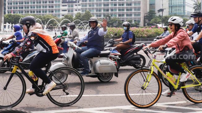 Gubernur DKI Jakarta Anies Baswedan (tengah) menaiki sepeda motor vespa saat melintas di Jalan Jenderal Sudirman, Jakarta Pusat, Minggu (16/10/2022). [Suara.com/Alfian Winanto]