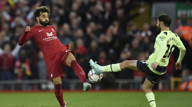 Striker Liverpool, Mohamed Salah (kiri) bersaing dengan gelandang Manchester City,  Bernardo Silva (kanan) selama matchday pekan ke-11 Liga Inggris antara Liverpool vs Manchester City di Anfield di Liverpool, barat laut Inggris pada 16 Oktober 2022.Oli SCARFF / AFP.