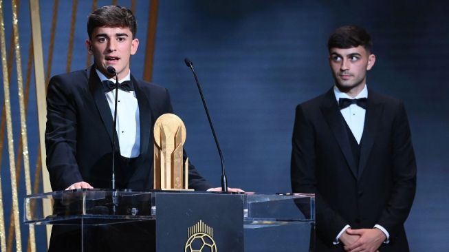 Gelandang Barcelona, Gavi (kiri) berbicara di atas podium usai meraih Trofi Kopa dalam seremonial Ballon d'Or 2022 di Theatre du Chatelet, Paris, Prancis, Selasa (18/10/2022) dini hari WIB. [FRANCK FIFE / AFP]