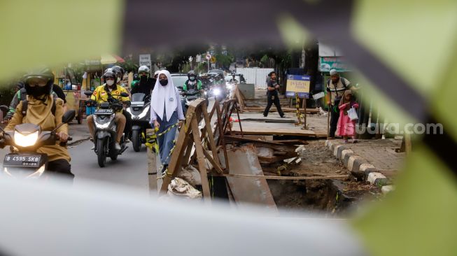 Pejalan kaki melintas disamping proyek galian saluran di Pejaten, Pasar Minggu, Jakarta Selatan, Selasa (18/10/2022). [Suara.com/Alfian Winanto]