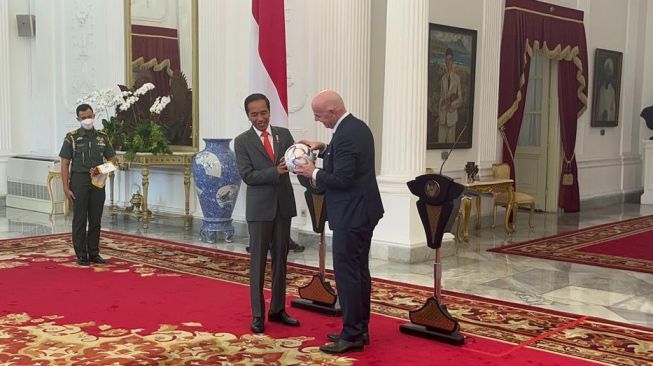 Presiden FIFA Gianni Infantino menyerahkan cinderamata kepada Presiden RI Joko Widodo dalam kunjungannya ke Istana Merdeka, Jakarta, Selasa (18/10/2022). [Suara.com/Ria Rizki Nirmalasari]