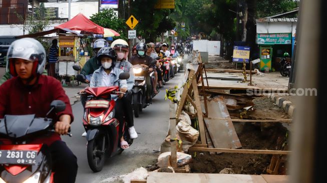 Pengendara melintas disamping proyek galian saluran di Pejaten, Pasar Minggu, Jakarta Selatan, Selasa (18/10/2022). [Suara.com/Alfian Winanto]