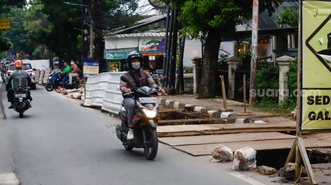 Pengendara melintas disamping proyek galian saluran di Pejaten, Pasar Minggu, Jakarta Selatan, Selasa (18/10/2022). [Suara.com/Alfian Winanto]