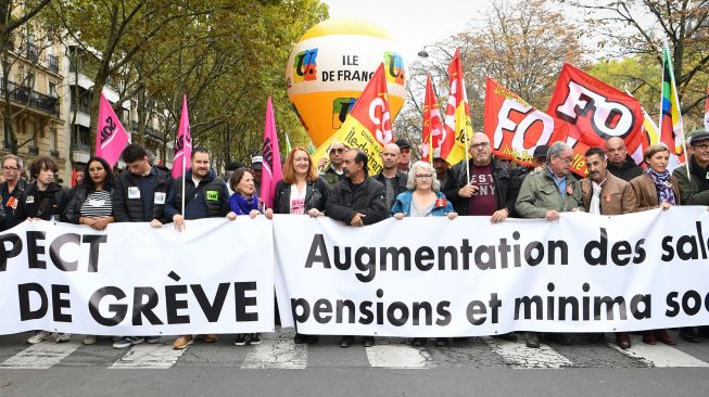 Para pengunjuk rasa memegang poster bertuliskan 'menghadapi kapitalisme, membalikkan diri!' selama demonstrasi di Paris, Prancis, Selasa (18/10/2022). [Bertrand GUAY / AFP]
