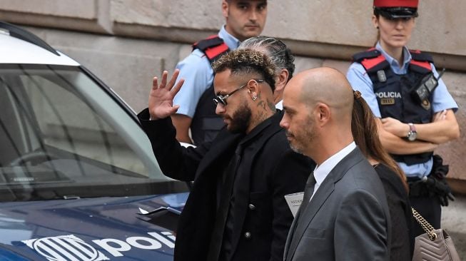 Pesepak bola Paris Saint-Germain Neymar menyapa awak media usai menghadiri sidang di gedung pengadilan di Barcelona, Spanyol, Senin (17/10/2022). [Pau BARRENA / AFP]
