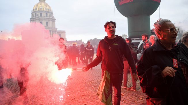 Seorang pengunjuk rasa membakar suar selama demonstrasi di Paris, Prancis, Selasa (18/10/2022). [Bertrand GUAY / AFP]
