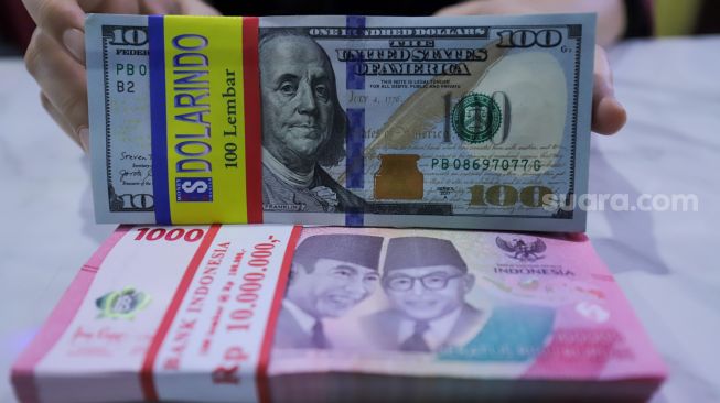 Petugas menunjukkan mata uang Rupiah dan Dolar AS di tempat penukaran uang Dolar Indo, Jakarta, Kamis (20/10/2022). [Suara.com/Alfian Winanto]