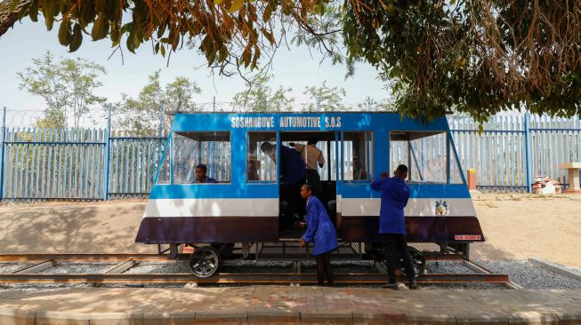 Siswa sekolah menengah teknik Soshanguve membersihkan kereta bertenaga surya yang mereka buat, di kotapraja Soshanguve, Pretoria, Afrika Selatan, Selasa (20/10/2022). [Phill Magakoe / AFP]
