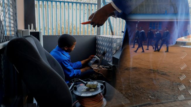 Siswa sekolah menengah teknik Soshanguve mengerjakan kereta bertenaga surya yang mereka buat, di kotapraja Soshanguve, Pretoria, Afrika Selatan, Selasa (20/10/2022). [Phill Magakoe / AFP]
