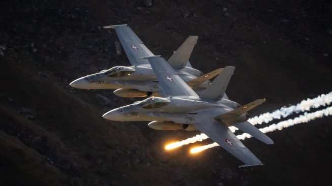 Dua pesawat McDonnell Douglas F/A-18 Hornet dari Angkatan Udara Swiss tampil dalam acara tahunan AXALP 2022 di di Bernese Oberland, Swiss, Rabu (19/10/2022). [Fabrice COFFRINI / AFP]