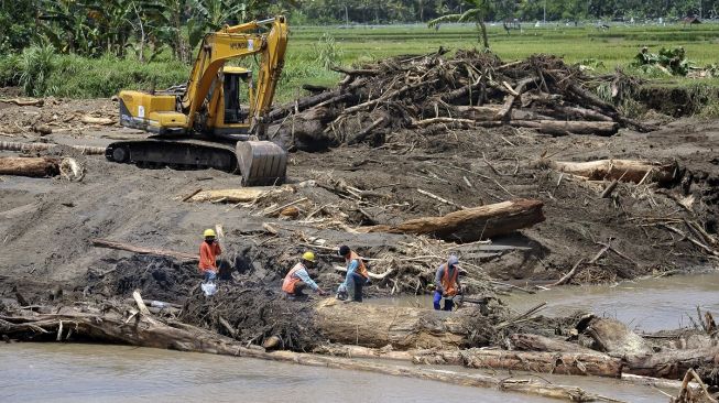 Pekerja membersihkan material kayu dan lumpur di sungai pascabanjir bandang di lingkungan Bilukpoh, Kelurahan Tegal Cangkring, Jembrana, Bali, Jumat (21/10/2022).[ANTARA FOTO/Nyoman Hendra Wibowo/nz]