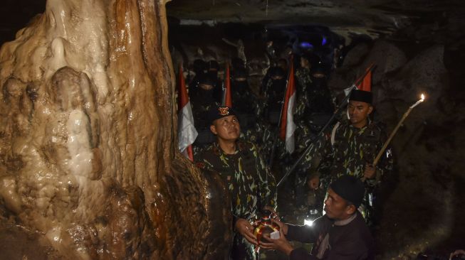 Danki 1 Batalyon D Pelopor Satbrimob Polda Jabar Iptu Enjang Sutisna (kiri) mengambil air suci di Goa Saparwadi Syech Abdul Muhyi, Pamijahan, Kabupaten Tasikmalaya, Jawa Barat, Kamis (20/10/2022). [ANTARA FOTO/Adeng Bustomi/nym].