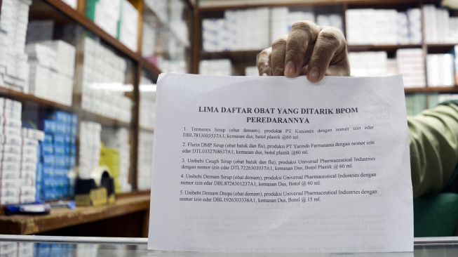 Seorang pedagang menunjukkan surat edaran larangan penjualan obat bebas dalam bentuk sirop di Pasar Pramuka, Jakarta, Jumat (21/10/2022).  ANTARA FOTO/Sulthony Hasanuddin