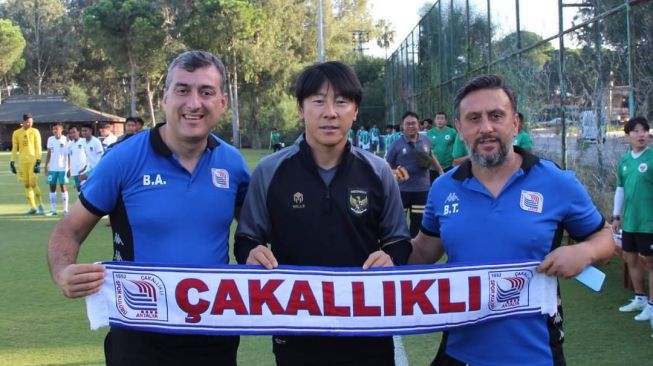 Pelatih Timnas Indonesia U-20, Shin Tae-yong berpose dengan syal tim lokal Turki, Cakallikli Spor jelang laga uji coba di Lapangan Kempinski Hotel Football, Antalya, Turki, Senin (24/10/2022). [Dok. Twitter/@cakallikli]