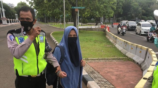 Polisi mengamankan seorang wanita berhijab nekat mengacungkan pistol kepada anggota Paspampres setelah berhasil menerobos di depan Istana Merdeka, Jalan Merdeka Utara, Jakarta Pusat, Selasa (25/10/2022). [Foto dok. Polisi/ ist]