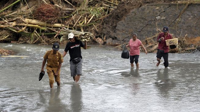 Perangkat desa dan warga menyeberangi sungai pascabanjir bandang di Dusun Sekar Kejula Kelod, Desa Yehembang Kauh, Jembrana, Bali, Selasa (25/10/2022). [ANTARA FOTO/Nyoman Hendra Wibowo/hp].