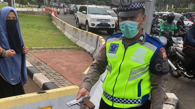 Anggota Polri menunjukan pistol yang dibawa wanita berhijab setelah berhasil menerobos di depan Istana Merdeka, Jalan Merdeka Utara, Jakarta Pusat, Selasa (25/10/2022). [Foto dok. Polisi/ ist]