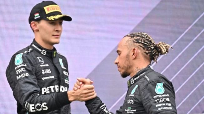 Pembalap Mercedes George Russell (kiri) berjabat tangan dengan rekan setimnya, Lewis Hamilton di dalam podium setelahnya F1 GP Hungaria di tempat Hungaroring dalam Mogyorod dekat Budapest, Hungaria, pada 31 Juli 2022.Attila KISBENEDEK / AFP