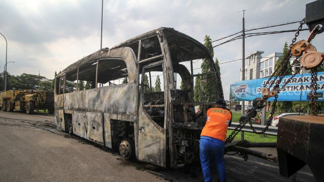 Petugas mengamati bus pariwisata bernopol AE 7388 UG yang terbakar di Gerbang Tol Otomatis (GTO) Menanggal Surabaya, Jawa Timur, Jumat (28/10/2022). [ANTARA FOTO/Umarul Faruq/aww].