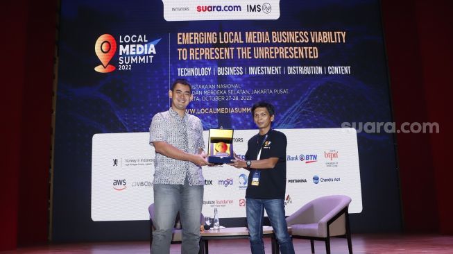 Redaktur Pelaksana Suara.com, Arsito Hidayatullah (kanan) memberikan piagam ke News Partnership Google Indonesia Yos Kusuma (kiri) saat menjadi pembicara workshop bertemakan "Business Ecosystem for Local Media Publisher" pada acara Local Media Summit 2022, di Gedung Perpusnas RI, Jalan Merdeka Selatan, Jakarta Pusat, Jumat (28/10/2022). [Suara.com/Alfian Winanto]