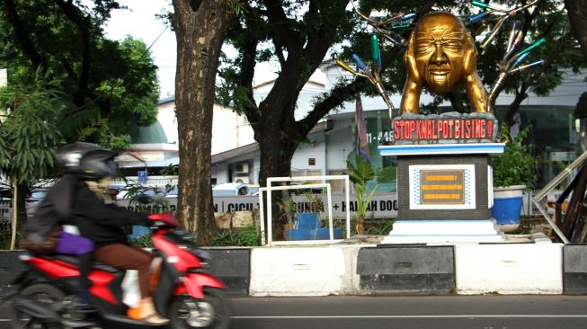 Pengendara melintas di dekat tugu anti knalpot bising di Makassar, Sulawesi Selatan, Sabtu (29/10/2022). ANTARA FOTO/Arnas Padda
