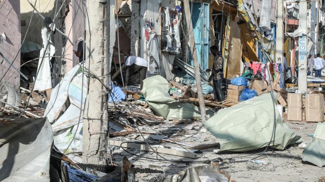 Warga menyelamatkan barang-barang dari bangunan yang hancur dan rusak setelah sebuah bom mobil meledak di Mogadishu, Somalia, Minggu (30/10/2022). [HASSAN ALI ELMI / AFP]