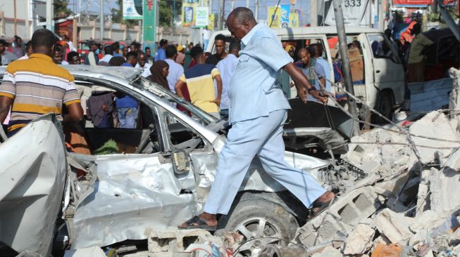 Warga berjalan di antara puing-puing bangunan yang hancur setelah sebuah bom mobil meledak di Mogadishu, Somalia, Minggu (30/10/2022). [HASSAN ALI ELMI / AFP]