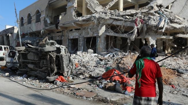 Seorang warga melihat puing-puing bangunan yang hancur setelah sebuah bom mobil meledak di Mogadishu, Somalia, Minggu (30/10/2022). [HASSAN ALI ELMI / AFP]
