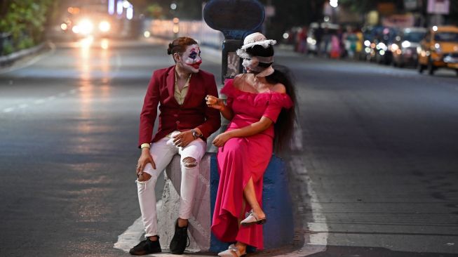 Para siswa yang mengenakan kostum berpose untuk foto saat mengikuti perayaan Halloween di sepanjang jalan di Kolkata, India, Minggu (30/10/2022). [Dibyangshu SARKAR / AFP]