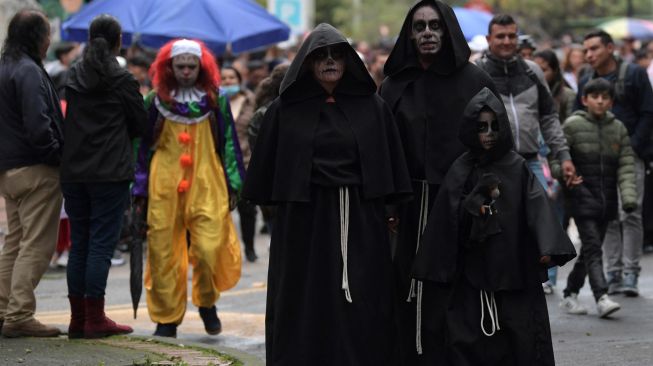 Orang-orang dengan kostum ambil bagian dalam 'Zombies March' saat perayaan Halloween di Bogota, Kolombia, Sabtu (29/10/2022). [Raul ARBOLEDA / AFP]