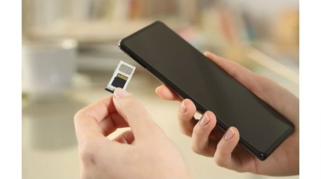 Ilustrasi memasukkan SD Card ke ponsel [Pheelings Media / Getty Images/Lifewire]