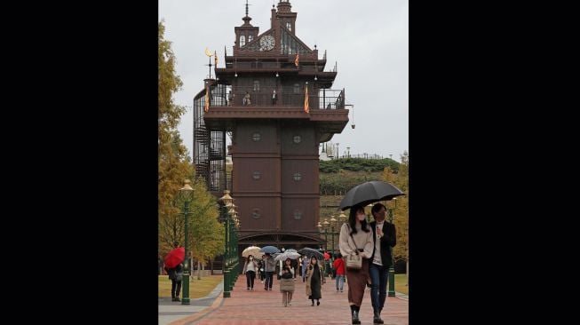 Pengunjung berjalan melewati "elevator tower" di dekat pintu masuk pada hari pertama pembukaan Taman Ghibli di Nagakute, prefektur Aichi, Jepang, Selasa (1/11/2022). [JIJI Press / AFP / Japan OUT]
